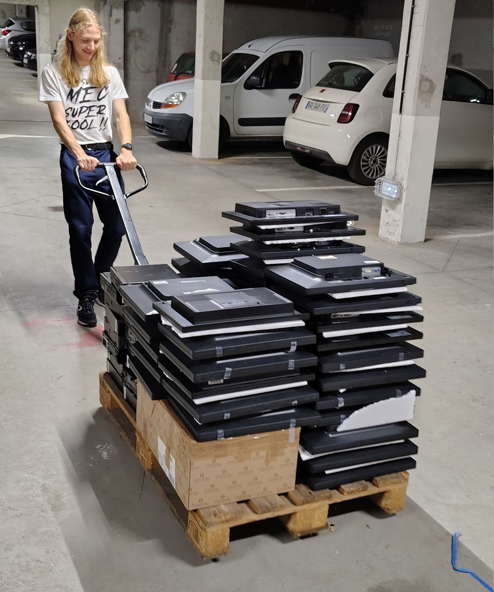 Un élève (souriant) réceptionnant des PC à reconditionner en Linux dans les combles du lycée Carnot.